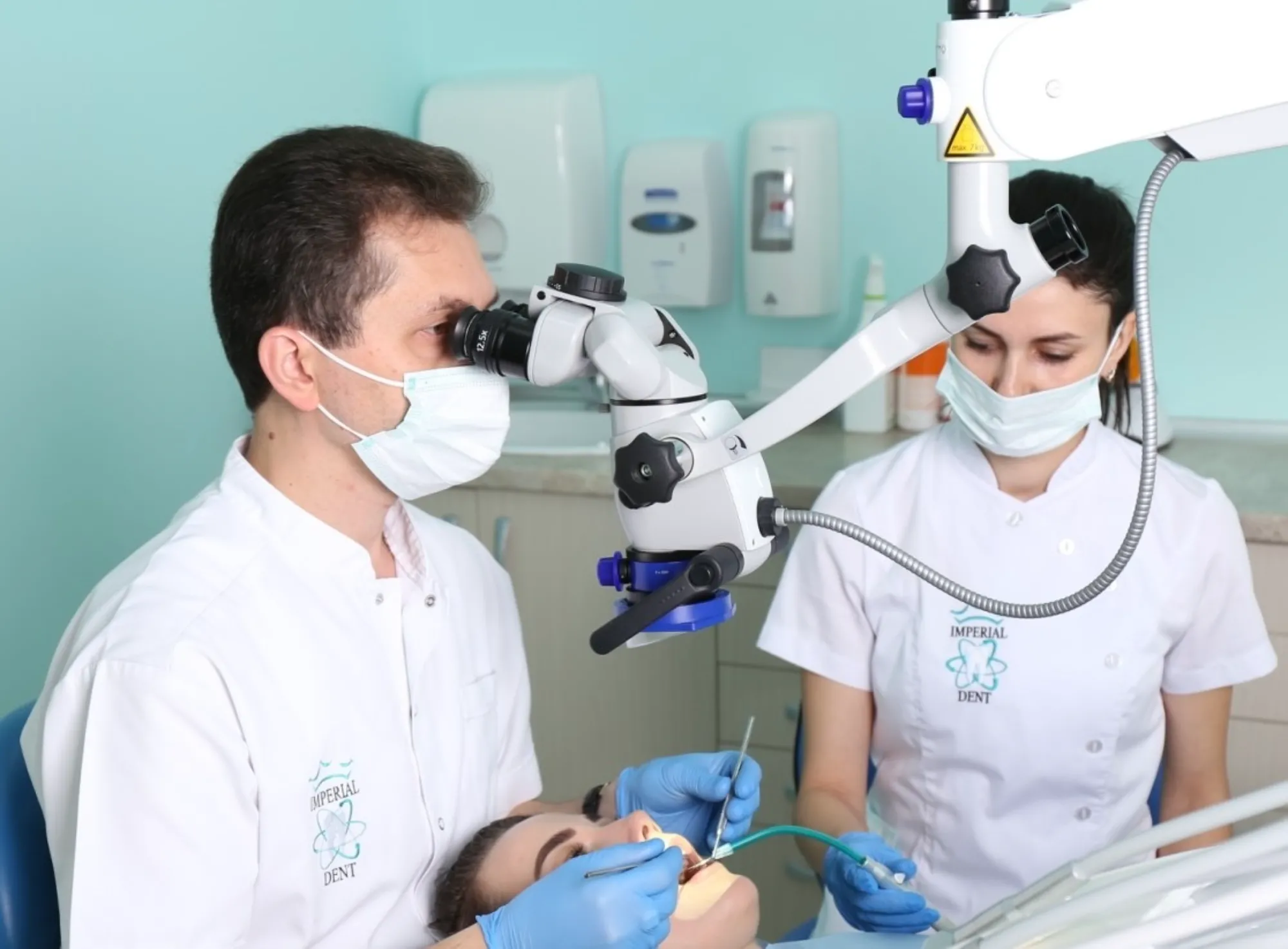 Doi medici lucrând cu microscopul dentar